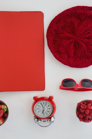 Overhead of fruits, file, sunglasses, alarm clock and beanie cap on white backgroundの写真素材