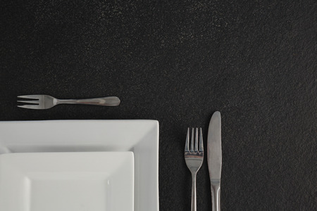 Close-up of square plates and cutlery set on a tableの写真素材