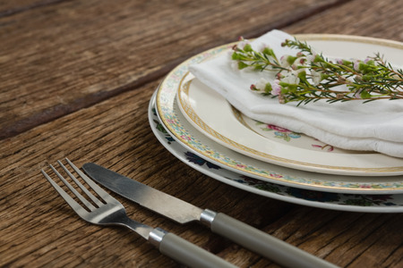 Close-up of fork and butter knife with napkin and flower arranged in a plate
