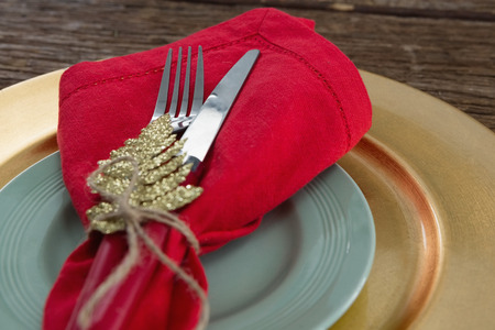 Close-up of fork and butter knife with napkin and christmas ornament tied up with a rope