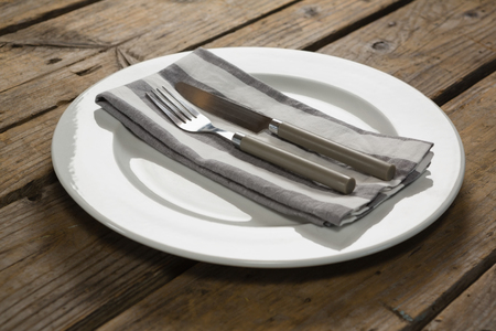 Close-up of fork and butter knife with napkin arranged in a plateの写真素材