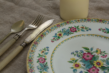 Close-up of floral pattern plate with cutlery set and candle