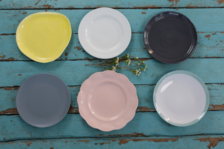 Overhead view of empty plates with flower on wooden table