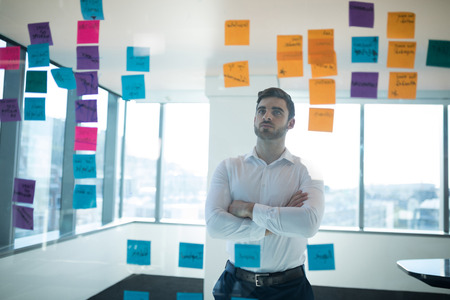 Male executive reading sticky note in office