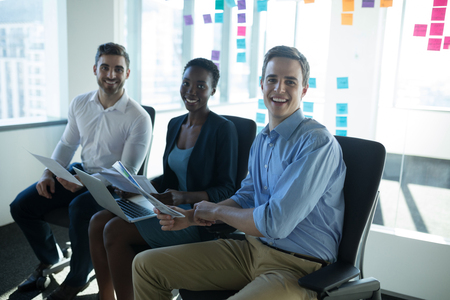 Portrait of smiling executives discussing over graph in officeの写真素材