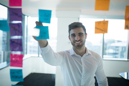 Male executive reading sticky note in office