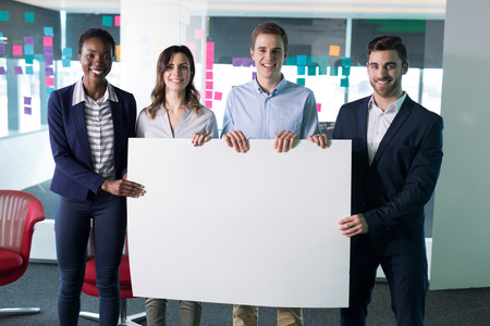 Portrait happy executives holding a blank banner in officeの写真素材