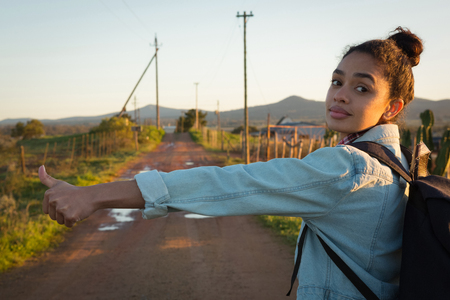 Young woman hitchhiking on a sunny dayの写真素材