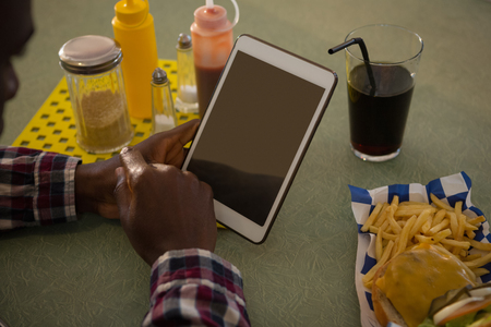 Close-up of man using digital tablet in restaurantの写真素材