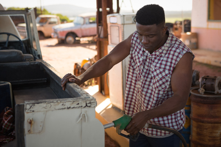 Man filling petrol in car at petrol pump on a sunny dayの写真素材