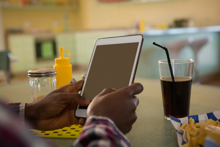 Close-up of man using digital tablet in restaurantの写真素材