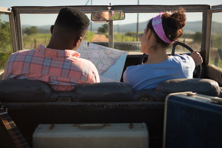 Couple looking at map while sitting in car at countrysideの写真素材