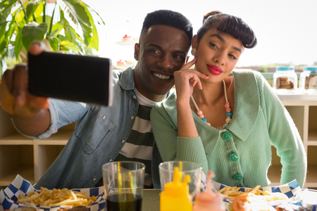 Couple taking selfie while having food in the restaurantの写真素材