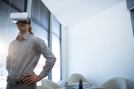 Male executive using virtual reality headset in waiting area of office Male executive using virtual reality headset in waiting area of office