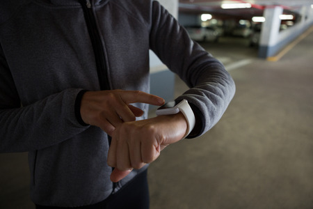 Mid section of fit woman using smartwatch in underground parking areaの写真素材