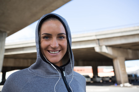 Portrait of smiling woman in hoodie listening to music on headphonesの写真素材