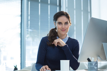 Portrait of female executive working on computer at deskの写真素材