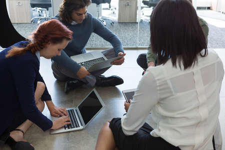 Business colleagues working on laptop and digital tablet in officeの写真素材
