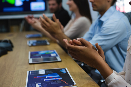 Business colleagues clapping hands in meeting at office