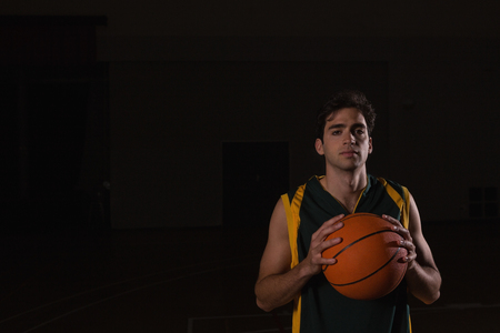 Portrait of basketball player holding ball in the courtの写真素材