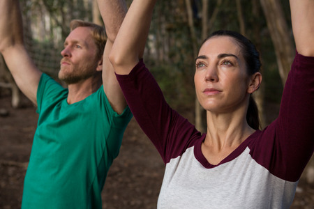 Close-up of woman performing stretching exercise with the help of trainer