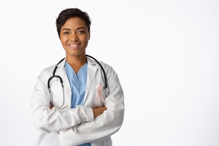 female doctor wearing breast cancer awareness pink ribbon with crossed arms on a white backgroundの写真素材