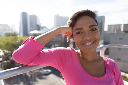 Smiling woman standing outside for breast cancer awareness against urban back groundの写真素材