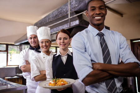 Group of hotel staffs standing with armas crossed in kitchen at hotelの写真素材