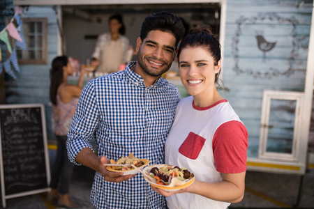 Portrait of smiling couple standing with snacksの写真素材