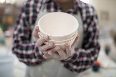 Proud male potter showing his creation to camera close up in the pottery workshopの写真素材