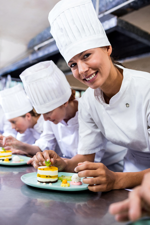 Group of chefs garnishing delicious desserts in a plate at hotelの写真素材