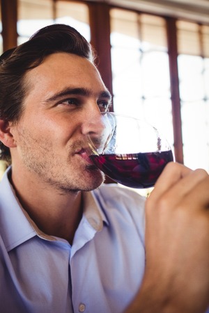 Close-up of man having red wine in restaurantの写真素材