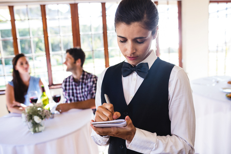 Female waitress writing order on notepad in restaurantの写真素材