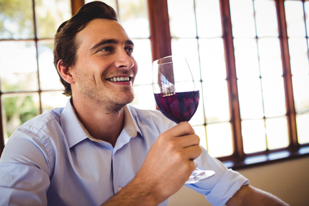 Happy man having red wine in restaurantの写真素材