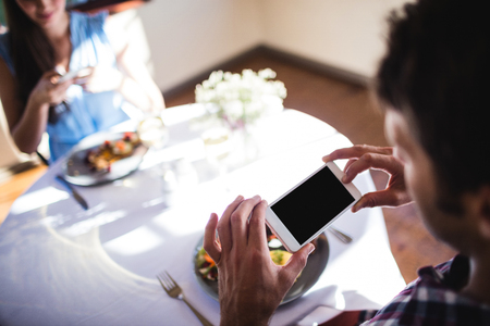 Couple clicking photo of a food on plate in restaurantの写真素材