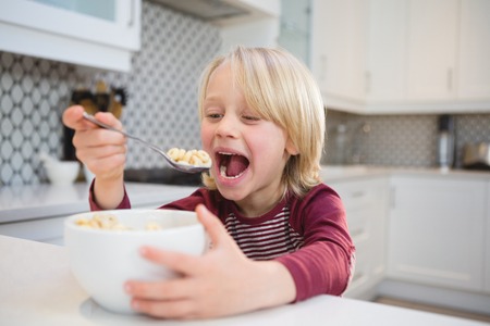 Happy boy having his breakfast at homeの写真素材