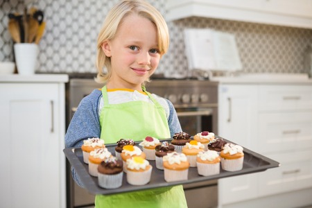 Portrait of boy holding a tray of muffins at home