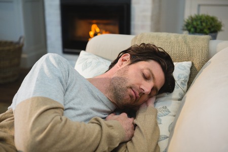 Man sleeping on sofa in living room at home