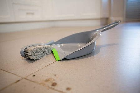 Close-up of dust pan and brush on a floor at homeの写真素材