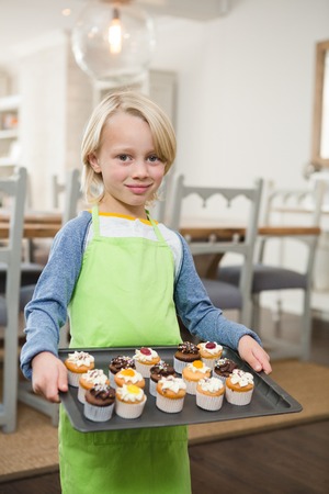 Portrait of boy holding a tray of muffins at homeの写真素材