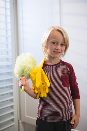 Portrait of boy holding a mop at homeの写真素材