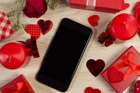 Heart shape decorations, gifts and mobile phone on wooden tableの写真素材