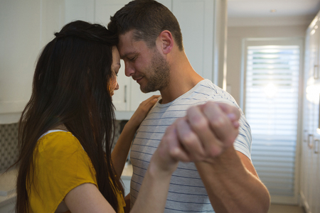 Couple dancing together in kitchen at homeの写真素材