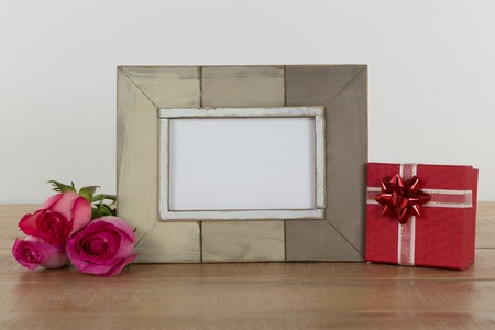 Rose flower, empty photo frame and gift boxes on wooden tableの写真素材