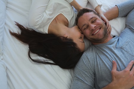 Couple lying on bed in bedroom at home