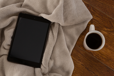 Close-up of digital tablet with blanket and black coffee on wooden backgroundの写真素材