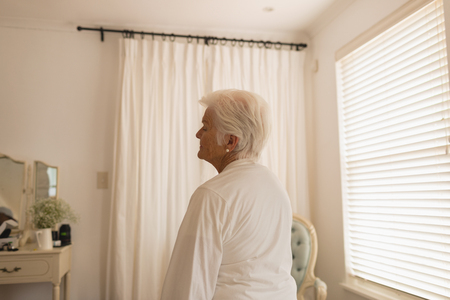 Back view of a senior woman relaxing and sitting in bedroom at homeの写真素材