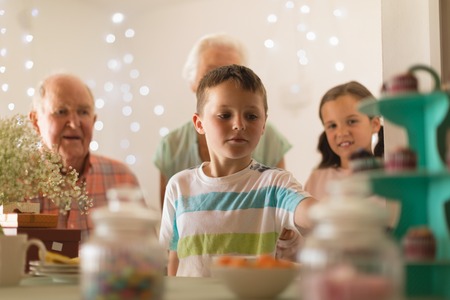 Happy multi-generation family celebrating birthday of grandson at table at home