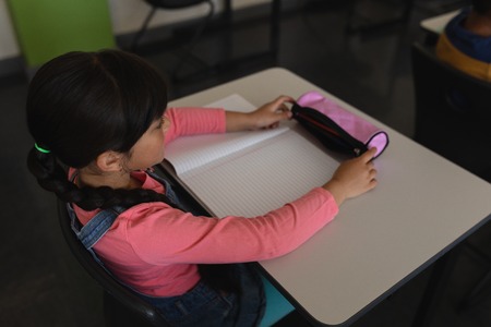 High angle view of schoolgirl studying in classroom sitting at desks in school