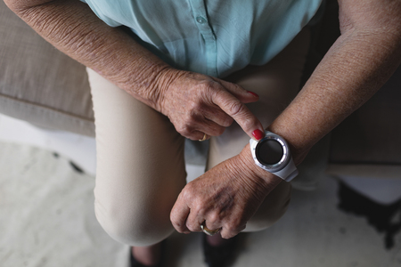 Close-up view of senior woman checking time on her wristwatch at homeの写真素材
